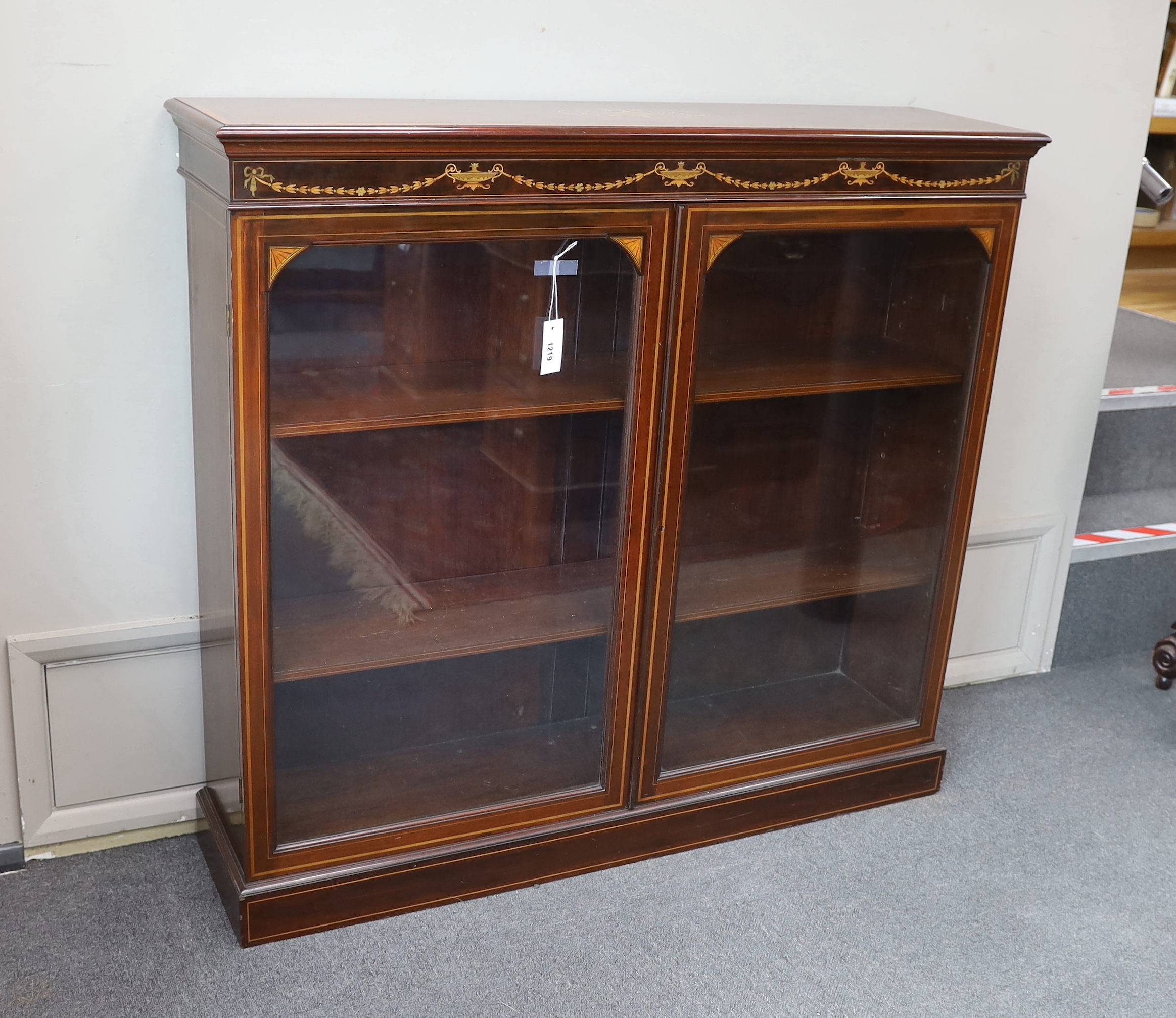 An Edwardian marquetry inlaid mahogany bookcase, bears Edwards & Roberts ivorine plaque, width 121cm, depth 31cm, height 111cm